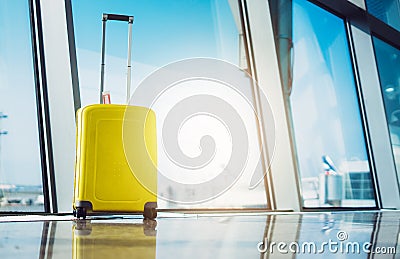 Isolate traveler tourist yellow suitcase at floor airport on background large window sun flare, bright luggage waiting in departur Stock Photo