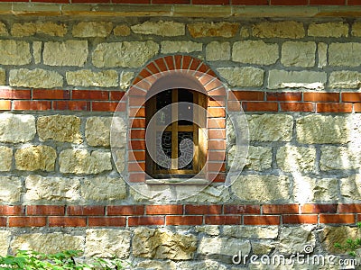 An isolated arched church monastery chapel window and massive stone wall background. Stock Photo