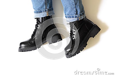 Isolated black unisex boots for winter and autumn with round toe, block heel and embossed hard sole on someone feet with Stock Photo