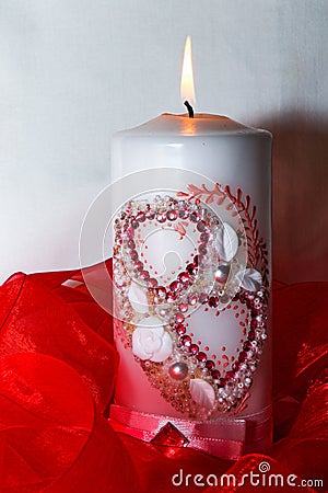 Isolated candle with hearts. Red ribbon. A burning candle. A bright flame. Decorative candle Stock Photo