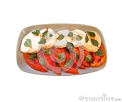 Isolated caprese salad of sliced tomatoes and mozzarella cheese rounds drizzled with balsamic vinegar & sprinkled with basil lea Stock Photo