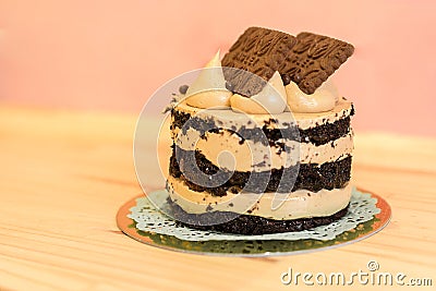 Isolated chocolate cake with cream and cookies on a wooden table. Pink background. Concept of bakery. Tasty and delicious cake. Stock Photo