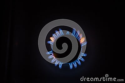 Isolated close up shot of a blue and orange circular fire with small flames on the perimeter coming from a kitchen gas stove and Stock Photo