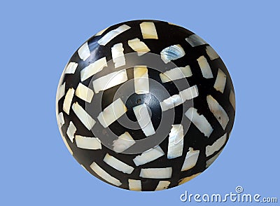 Isolated closeup of a black spiracle stone with mother of pearl chips embedded on a blue background Stock Photo