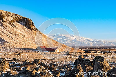 An isolated farmouse sits at the foot of a mountain in Iceland Stock Photo