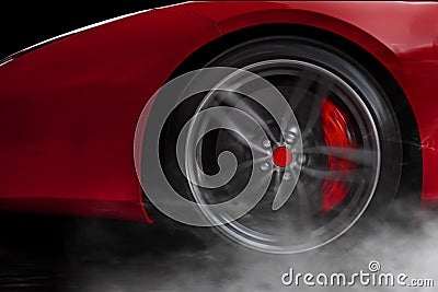 Isolated generic red sport car with detail on wheel with red breaks drifting and smoking on a dark background Stock Photo