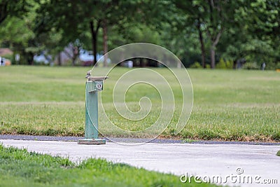 Isolated green drinking water water fountain on a pathway in an empty park Stock Photo