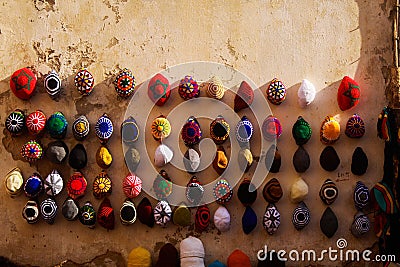 Isolated knitted moroccan can hats hanging in a row on wall in bright evening sun - Essaouira, Morocco Editorial Stock Photo