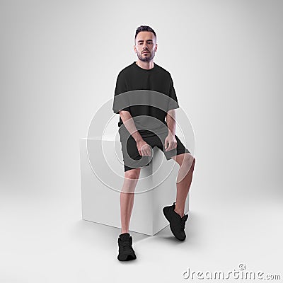 Isolated mockup of trendy black men`s oversized t-shirt with shorts on man sitting on cube Stock Photo