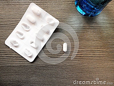 Isolated pill next to the package of pills with a glass of water Stock Photo