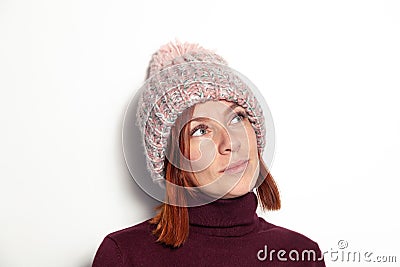 Portrait of beautiful young redhead girl with green eyes pink knitted hat with pompon dressed sideways smiling on white background Stock Photo