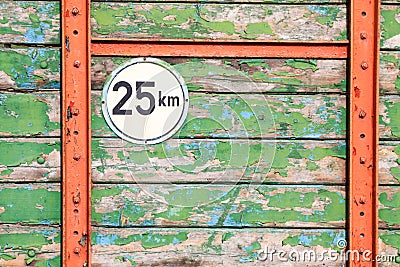 Isolated round metal speed limit 25 km sign on weathered colorful wooden planks with peeling paint on back of agricultural trailer Stock Photo