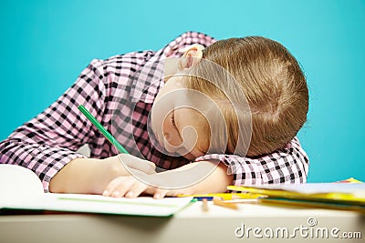 Isolated shot of child with poor posture sitting at desk and do homework. Girl rested her head on table and writes in Stock Photo