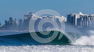 Isolated shot of a foaming sea wave in the background of a resort buildings Stock Photo