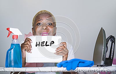 Isolated young attractive and unhappy black afro American woman on kitchen iron board holding notepad with help text written feeli Stock Photo