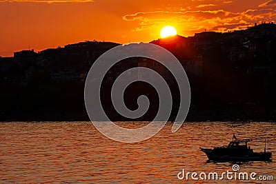 Istanbul, Beylikduzu - Turkey - 04.30.2023: silhouette of istanbul, orange color sunset, small boat and calm sea side. early Editorial Stock Photo