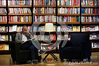 Istanbul, Istiklal Street / Turkey 9.5.2019: Salt Beyoglu Art Center, Men Reading a Book in front of the Bookshelf Editorial Stock Photo