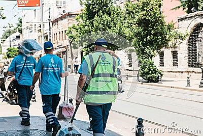 Istanbul, June 15, 2017: Three street janitors in uniforms are walking down the street holding brooms and dust pans. Editorial Stock Photo