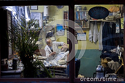 ISTANBUL, TURKEY - DECEMBER 29, 2015: Old barber shaving one of his client at night, in an old fashionned barber shop on the Europ Editorial Stock Photo