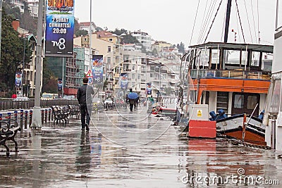 Istanbul Turkey January 31 2019: A man walking down the docks on rainy day. Orange transportation boat is moored on the docks. Editorial Stock Photo