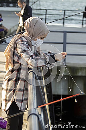 Young woman fisherman with a fishing rod on the shores of the Bosphorus. ÃœskÃ¼dar Editorial Stock Photo