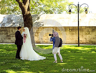 Istanbul. Turkey. May 5, 2016: Photographer takes a picture of a beautiful muslim wedding couple in the park Editorial Stock Photo