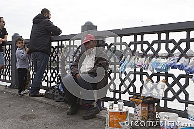 ISTANBUL / TURKEY - 30/05/2015: old tired Turkish street vendor of fishing lines, hooks, rigs, sitting and sleeping on Galata Editorial Stock Photo