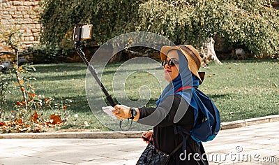 Istanbul, Turkey, September 2018: Young slightly overweight Asian woman with straw hat and sunglasses smilingly makes a selfie in Editorial Stock Photo