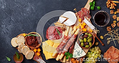 Italian appetizers or antipasto set with gourmet food on black table top view. Delicatessen of cheese and meat snacks with wine Stock Photo