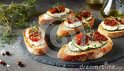 Italian bruschetta bread with cream cheese, zucchini and dried tomato with herbs. Canape with ricotta cheese Stock Photo