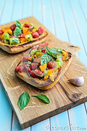 Italian bruschetta with chopped tomatoes and basil on wooden cutting board Stock Photo