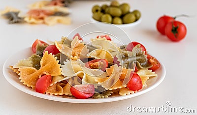 Italian colored pasta with basil and tomatoes on a light plate. Stock Photo