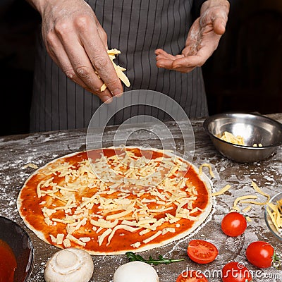 Italian Cuisine. Cook Hand Adding Grated Cheese To Pizza Stock Photo
