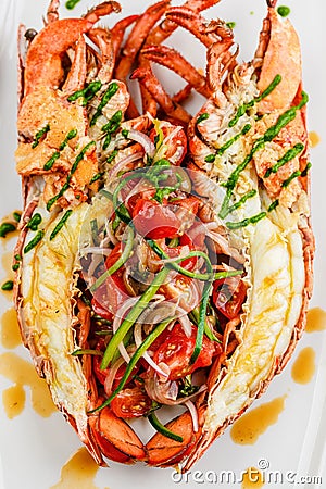 Italian cuisine. Whole lobster baked and sliced in half Served with tomato salad and sauce on white plate Stock Photo