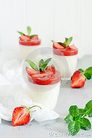 Italian dessert Panakota with strawberry coolies, fresh berries and mint on a white background with hard shadows. Stock Photo