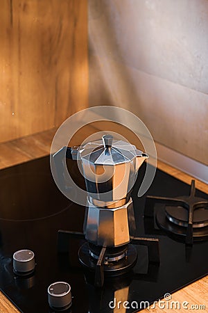 An Italian espresso mokka machine with steam getting out of it while making a fresh coffee in a regular kitchen with wood and ston Stock Photo