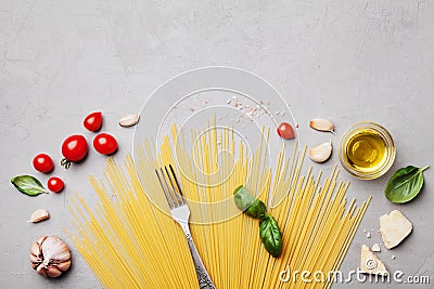 Italian food background with uncooked spaghetti, tomato, basil leaves, cheese, garlic and olive oil for cooking on stone table Stock Photo
