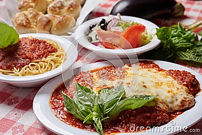 Italian food combination of lasagna, small side salad and garlic knots with whole raw vegetables on the background Stock Photo