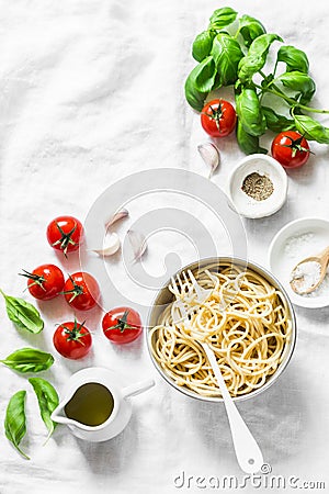 Italian food pasta background with copy space on white background, top view. Basil, whole grain spaghetti, cherry tomatoes, olive Stock Photo