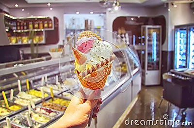 Italian ice - cream cone held in hand on the background of shop Stock Photo