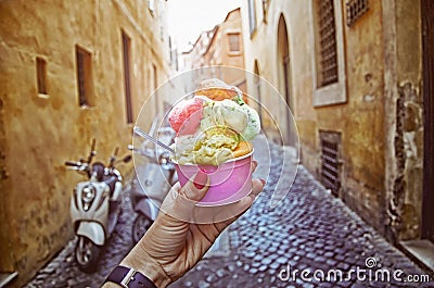 Italian ice - cream cone held in hand on the background of on vintage street atmosphere Stock Photo