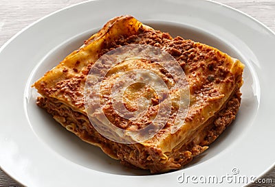 Italian meat Lasagne in a white dish on wooden background. Portion of traditional Lasagna Stock Photo