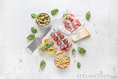 Italian or mediterranean food cuisine and ingredients on white concrete table. Tagliatelle pene pasta olives olive oil tomatoes Stock Photo