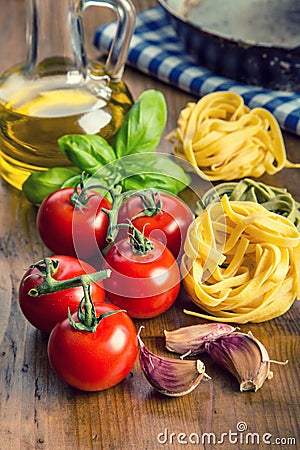 Italian and Mediterranean food ingredients on wooden background.Cherry tomatoes pasta, basil leaves and carafe with olive oil. Stock Photo
