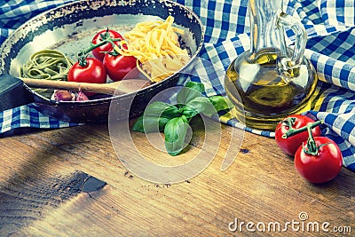 Italian and Mediterranean food ingredients on wooden background.Cherry tomatoes pasta, basil leaves and carafe with olive oil. Stock Photo