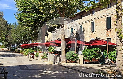 Italian outdoor cafe with umbrellas and flower pots in small tow Stock Photo