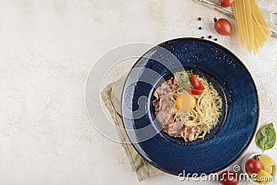 Italian pasta carbonara with ham, cheese and egg on a blue plate with a napkin on a light background Stock Photo
