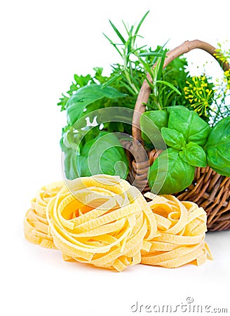 Italian pasta fettuccine nest with wicker basket green herbs Stock Photo