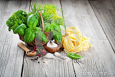 Italian pasta fettuccine nest with wicker basket green herbs Stock Photo