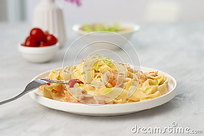 Italian pasta fettuccine with shrimps in white bowl on gray table. Close up beautiful picture homemade national cuisine Stock Photo